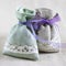 Two small linen sacks filled with dried lavender decorated with lacework and violet ribbon coque, aroma sachet. Closeup