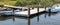 Two small motor boats tied to a dock in beach grass