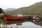 Two small red fishing boats along a river in rural Connemara in western Ireland