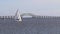 Two small sailboats salining in the winter passing the Great South Bay bridge on Long Island