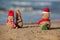 Two small sandy snowmen and santa at tropical beach.