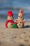 Two small sandy snowmen at tropical beach.