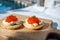 Two small starters blinis with sour cream and salted salmon red caviar served on mango tree wooden board