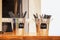 Two small tin buckets on counter at restaurant holding plastic cutlery - knives and forks - selective focus with bold blocked