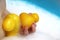 Two small yellow ducks in the child`s hand are pressed to the body. Around the foam for the bathroom. blue background