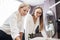 Two smart-looking pretty women wearing white shirts are leaning over the sewing table. Fashion, tailor`s workshop.