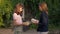 Two smart teenage girls exchanging books in slow motion at sunset in spring summer park. Side view portrait of confident