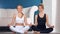 Two smiling adorable woman practicing yoga sitting lotus position posing looking at camera