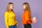 Two smiling blonde twins sisters girls in vivid clothes hold red striped present box with gift ribbon  on violet