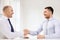 Two smiling businessmen shaking hands in office