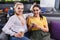 two smiling businesswomen with coffee and smartphone at modern coworking