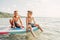 Two smiling Caucasian boys kids sitting on paddle sup surfboard in water.