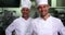 Two smiling chefs giving thumbs up to camera