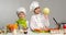 Two smiling children-cooks by the table with vegetables