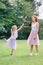 Two smiling funny Caucasian girls sisters wearing pink tutu tulle skirts in park forest meadow at sunset. Friends having fun