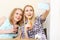 Two smiling girls doing selfie in cafe