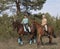 Two smiling girls horseback rides .