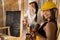 Two smiling girls ready to start work on a construction site. Blonde and dark haired. A lady engineer and a young