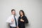 Two smiling happy businesspeople in formalwear showing thumbs-up on gray