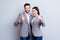 Two smiling happy businesspeople in formalwear showing thumbs-up on gray background