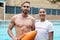 Two smiling lifeguards standing at poolside