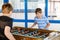 Two smiling school boys playing table soccer. Happy excited children having fun with family game with siblings or
