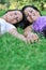 Two smiling sisters lying outdoors in grass