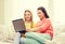 Two smiling teenage girls with laptop at home