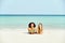 Two smiling women in bikinis suntanning on a tropical beach