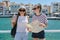 Two smiling women mother and teenager daughter with map on shore of sea bay