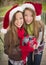 Two Smiling Women Santa Hats Holding a Wrapped Gift