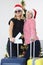 Two smiling women stand with suitcases against background of New Year tree