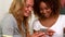 Two smiling young female friends reading text message