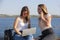 Two smiling young girls using laptop at the park, laughing, chatting