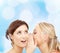 Two smiling young women whispering gossip