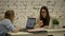 Two smilling businesswomen working on laptop at office