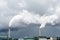 Two smokestacks emitting white smoke against a stormy sky