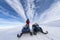 Two snowmobiles stand in a row with a boy at left one. He dressed for driving in cold mountains