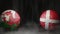 Two soccer balls in flags colors on a black abstract background. Wales and Denmark.