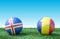 Two soccer balls in flags colors on green grass. Iceland and Romania.