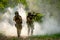 Two soldiers with the fighting uniform walk on the ground and point gun to enemy for the concept of battle in war