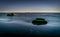 Two solitary rock in a flat sea at night