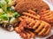 Two southern fried chicken fillets, green fresh salad and fancy cut potato lattice served on a white plate. Poultry meat dinner.