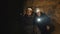 Two speleologists with flashlight exploring the cave with fear in darkness