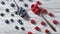 Two spoons with red juicy ripe berries - raspberry and blueberry and around them on a gray wooden background.