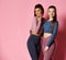 Two sport girls international friends in modern high-tech colorful sportswear posing on pink