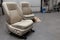 Two sport seats with beige leather trim, located on the floor in the workshop for repair and tuning of cars and vehicles. Auto