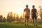 The two sportsmen standing on the grass on the sunset background.