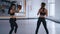 Two sportswomen in black fitness suits are engaged in a pair, training kicks. Athlitic women kickboxers training fight