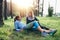 Two sporty girlfriends relaxing, lying on grass and chatting in the forest after jogging together